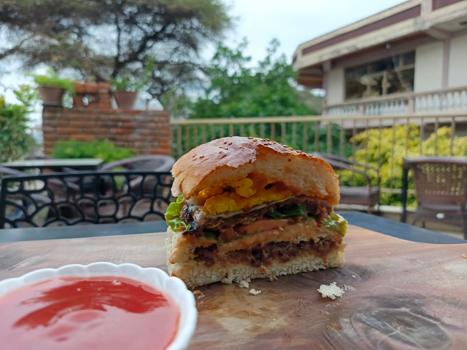 YO Burger's signature burger, cut open on a wooden board with ketchup, on the terrace in Adama