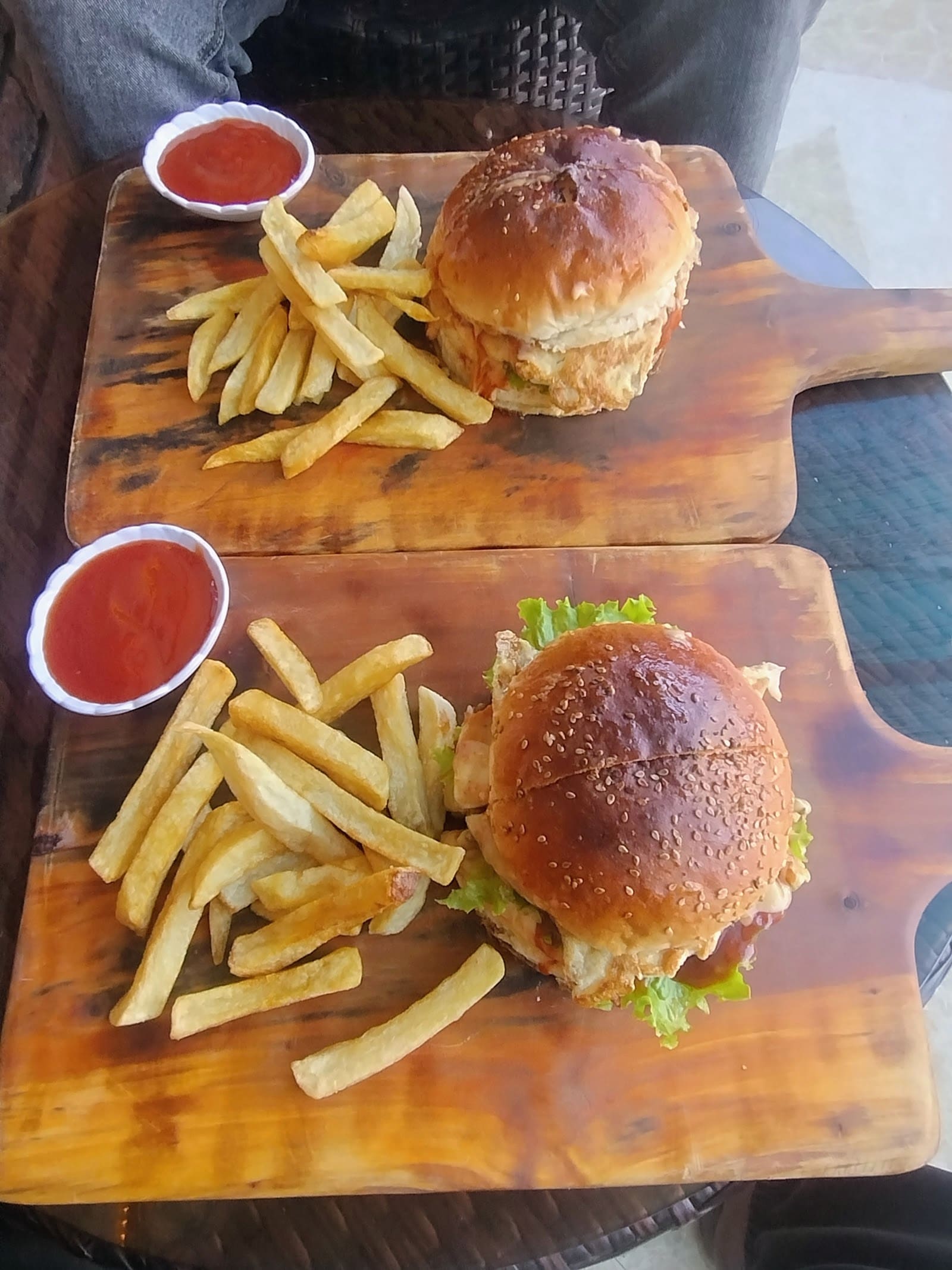 Two burger boards with chips and ketchup